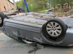 Řidička narazila se svým Superbem do kamenné zídky, urvala kolo a auto přetočila na střechu