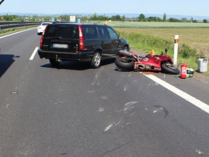 Motorkář předjížděl kolonu na dálnici po středové čáře. Srazil se s autem a skončil v nemocnici